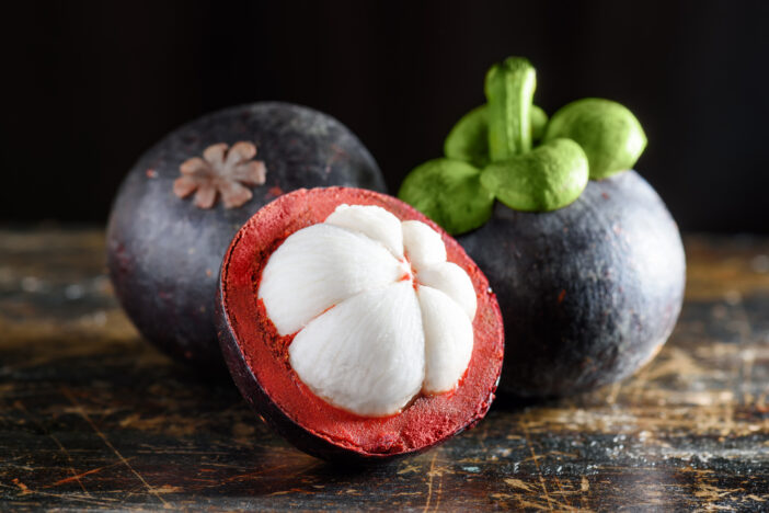 Closeup view of fresh ripe mangosteen on wooden table. Juicy tropical fruit with sweet white flesh. Healthy eco food. Freshly harvested fruits.