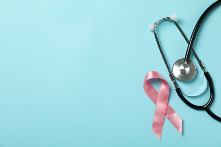 Pink awareness ribbon and stethoscope on a blue background